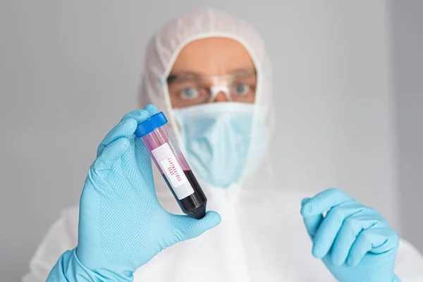 Científico en traje protector sosteniendo tubo de ensayo con sangre — Foto de Stock
