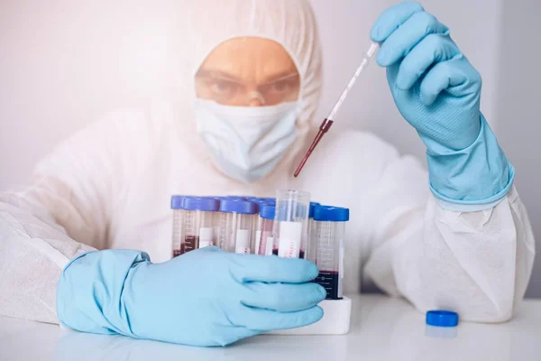 Científico en laboratorio que trabaja con tubos sanguíneos de prueba . — Foto de Stock