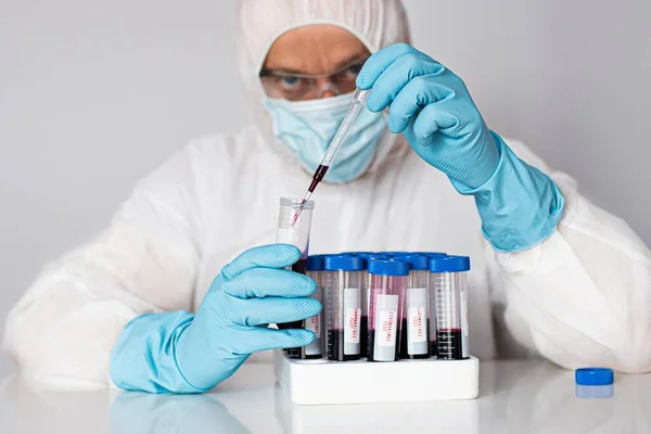 Científico en laboratorio que trabaja con tubos sanguíneos de prueba . — Foto de Stock
