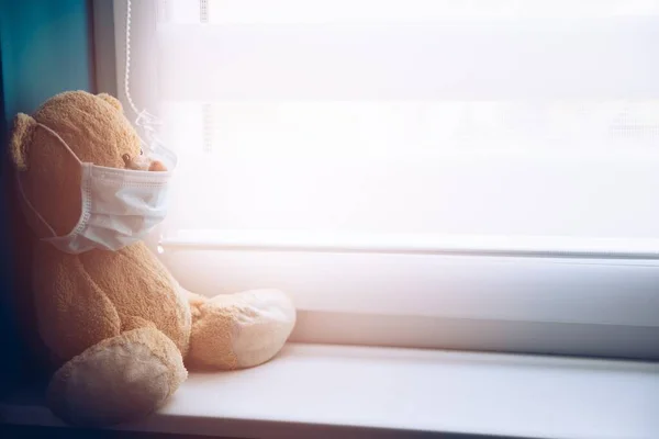 Mascotte orso sul davanzale di una finestra di un ospedale in una maschera medica . — Foto Stock