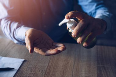 Evde çalışan ve eli antibakteriyel jelle dezenfekte eden adam..