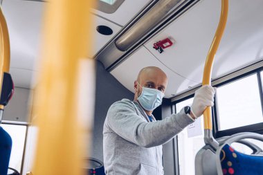 Otobüste tıbbi maske takan ve koruyucu eldiven takan bir adam. covid-19 sırasında toplu taşıma