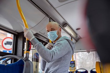 Otobüste tıbbi maske takan ve koruyucu eldiven takan bir adam. covid-19 sırasında toplu taşıma