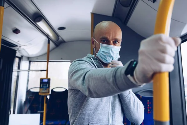 Mann mit Schutzmaske und Schutzhandschuhen im Bus. Öffentliche Verkehrsmittel während der covid-19 — Stockfoto