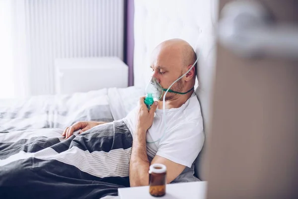 Hombre respirando a través de la máscara de oxígeno en la cama. Paciente de Covid-19 . — Foto de Stock