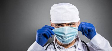 Beyaz takım elbiseli sıhhiye doktoru, koruyucu eldivenler ve sağlık maskesi kartıyla evde kalın.