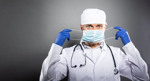 Medic arts in wit pak, beschermende handschoenen en medisch masker holding card met bericht thuis blijven — Stockfoto