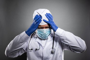 Beyaz üniformalı ve tıbbi maskeli çok yorgun bir doktor..