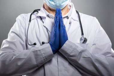 Tıbbi koruyucu maskeli yorgun doktor dua ediyor..
