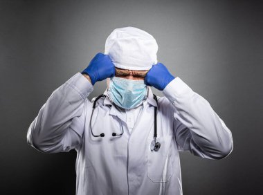 Beyaz üniformalı ve tıbbi maskeli çok yorgun bir doktor..