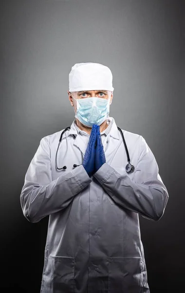 Müder frustrierter Arzt in medizinischer Schutzmaske betet. — Stockfoto