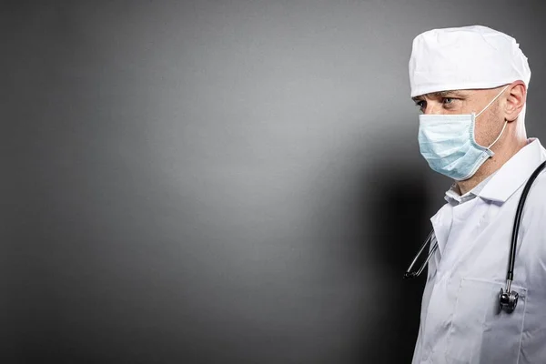 Dokter in medisch masker op grijze achtergrond. Kopieerruimte — Stockfoto