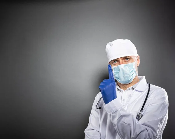 Médecin en uniforme blanc et masque médian protecteur pointant vers le haut — Photo