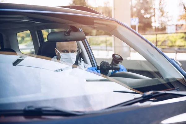 Mann mit medizinischer Schutzmaske fährt Auto — Stockfoto