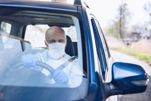 Mann fährt Auto mit medizinischer Schutzmaske. — Stockfoto