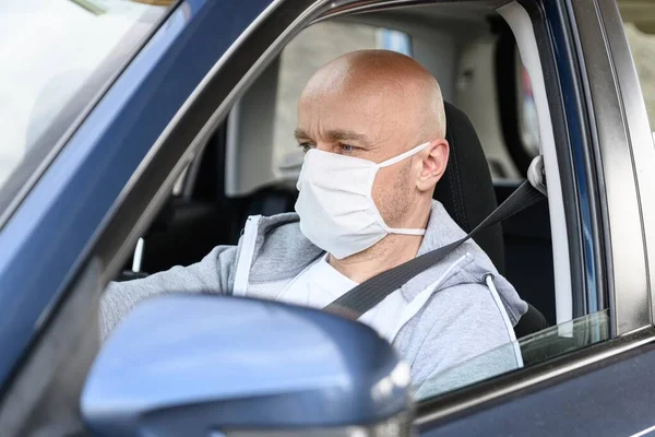 Mann fährt Auto mit medizinischer Schutzmaske. — Stockfoto