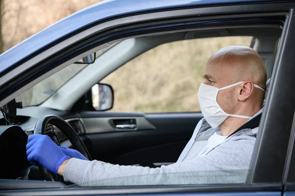 Hombre conduciendo un coche en máscara de protección médica . — Foto de Stock