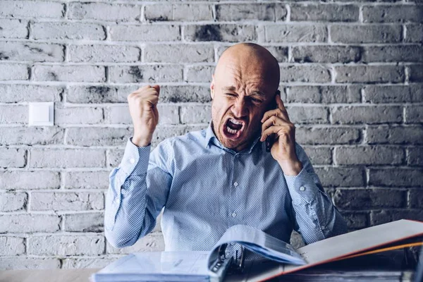 Rozzlobený muž v košili zuřivě mluví po telefonu — Stock fotografie