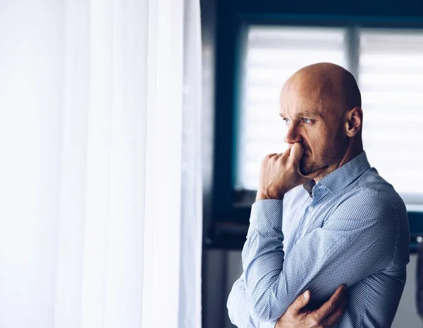 Un hombre de negocios preocupado en el cargo. Un hombre reflexivo mirando por la ventana . — Foto de Stock