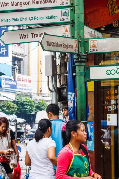 People walking past a street direction sign — Stock Photo, Image