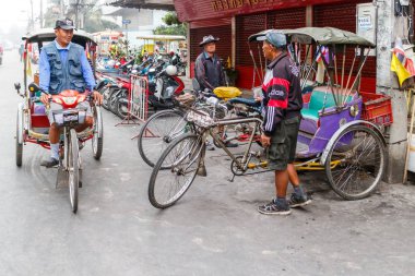 Rickshaw şoförleri iş için bekliyor.