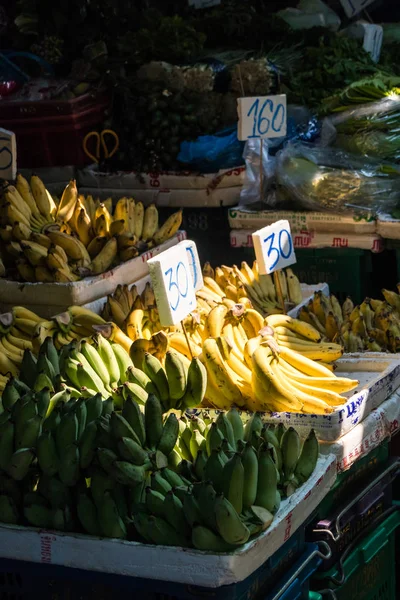 Plátanos en un puesto de mercado resaltado por un rayo de luz solar . — Foto de Stock