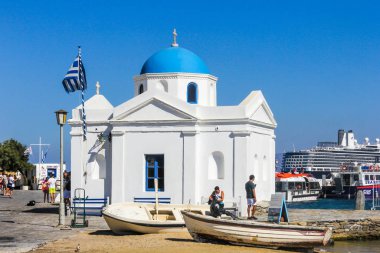 Mykonos, Yunanistan - 23 Temmuz 2016: Arka planda bir yolcu gemisi bulunan limandaki kilise. Ada popüler bir tatil beldesi..