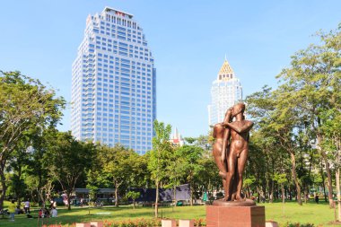 Bangkok, Tayland - 20 Eylül 2009: Arkasında ofis binaları olan Lumphini Park 'taki heykel. Burası şehrin ana dinlenme alanı.