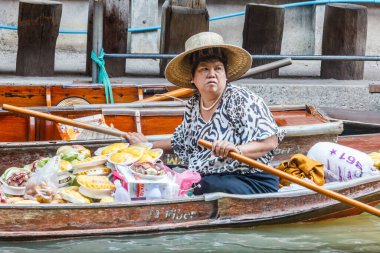 Damnoen Saduak, Tayland - 4 Mart 2017: Meyve satıcısı teknesini yüzdürüyor. Yüzen piyasa popüler bir turist karmaşasıdır.