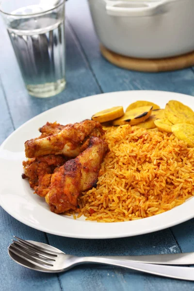 Jollof rice mit huhn und gebratenem wegerich, westafrikanische küche — Stockfoto