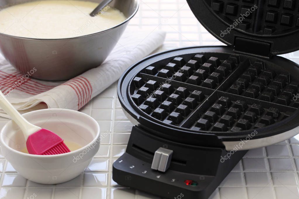 preparing homemade waffles by waffle maker machine.