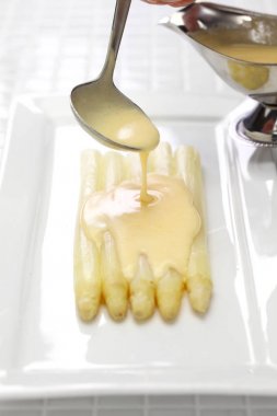 Hollandaise sosu beyaz kuşkonmaz dökülür.