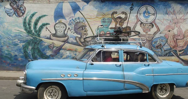 老蓝色美国汽车在古巴在街道在墙壁绘画前面 — 图库照片