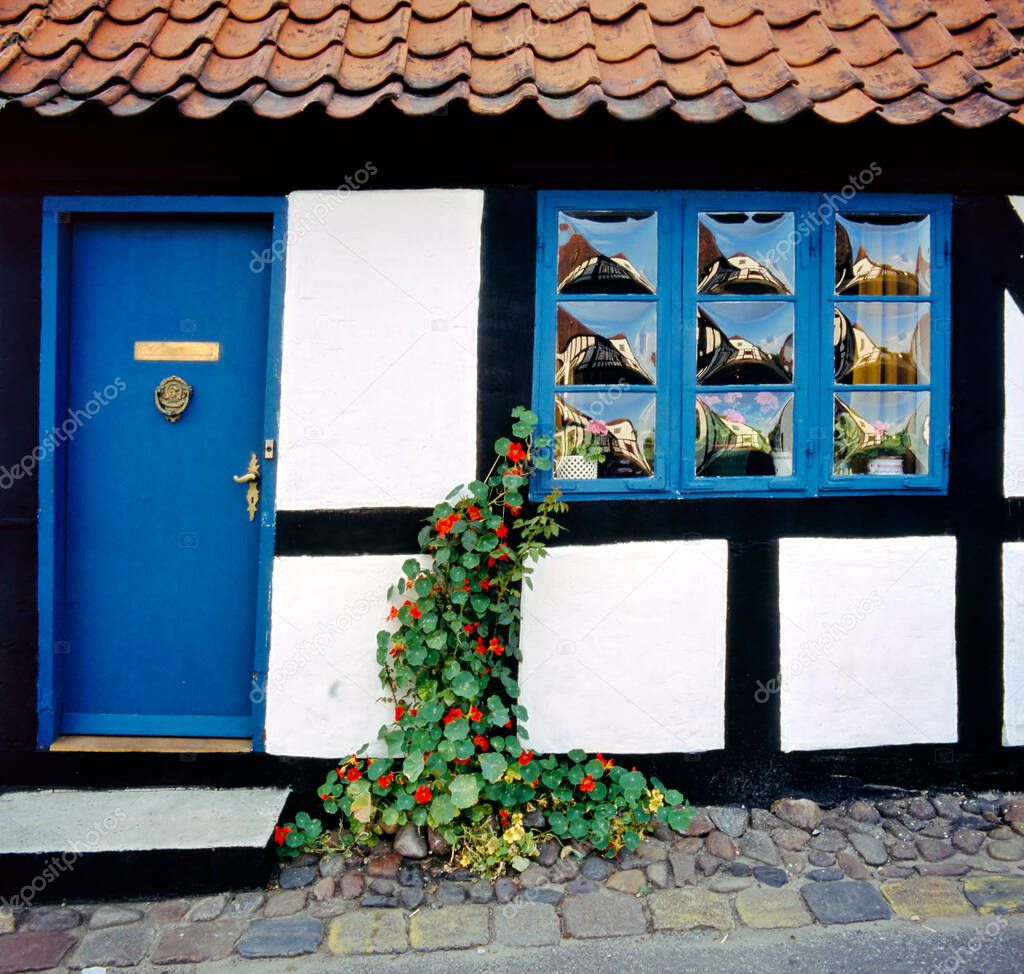 A traditional cottage in Ebeltoft, Denmark, with special windows alongside a cobbled stone street