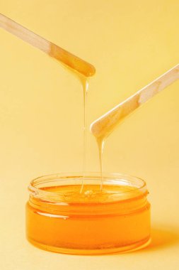 Sarı arka planda bal, tüy dökmek için spatula, tüy dökmek için doğal mum.