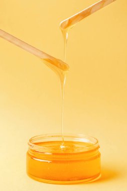 Sarı arka planda bal, tüy dökmek için spatula, tüy dökmek için doğal mum.