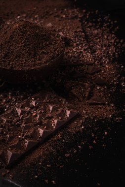 Kakao çekirdekleri, kakao tozu, kakao yağı, çikolata ve çikolata sosu, ahşap bir kasede çikolatalar mesaj atmak için arka planda.