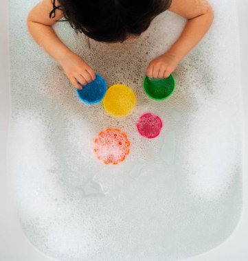 Genç kız banyo yapıyor ve küvette oynuyor.