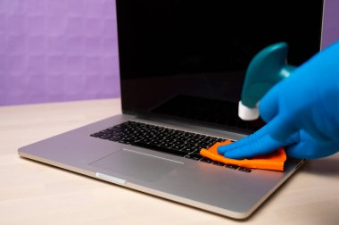 Dezenfektan spreyi ve eldivenlerle dizüstü bilgisayarı temizleyip dezenfekte etmek. Bilgisayar yüzeylerini virüsten, mikroplardan ve pislikten temizliyorum. Coronavirus Önleme.