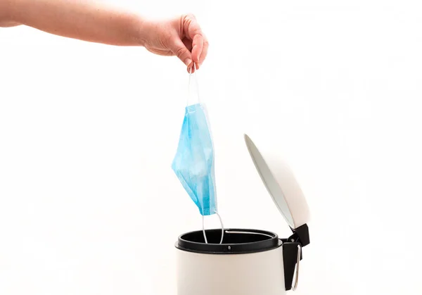 El koruyucu yüz maskesini çöp kutusuna atıyor. Coronavirüs kavramının sonu. Covid-19 tedavisi gördü ve karantina sona erdi. Beyaz arkaplan