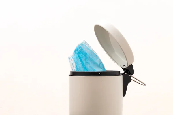 Koruyucu yüz maskesi çöp kutusuna atıldı. Coronavirüs kavramının sonu. Covid-19 tedavisi gördü ve karantina sona erdi. Beyaz arkaplan