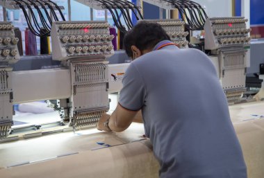 İşçi, giyim endüstrisinde nakış makinesi kurdu.