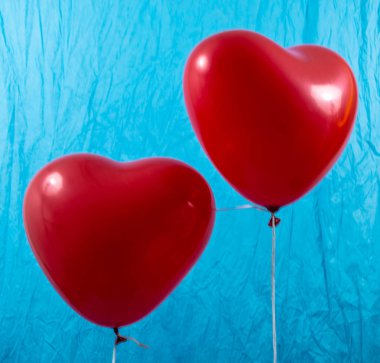 Mavi bir arka plan üzerinde kırmızı kalp balonlar
