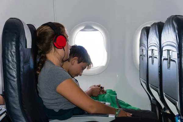 Мальчик и девочка слушают музыку сидя в самолете — стоковое фото