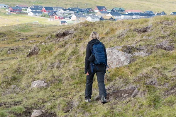 Žena s batohem chodí na kopcích, na Faerských ostrovech — Stock fotografie