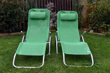Green deck chairs in the garden. Relaxing concept clipart