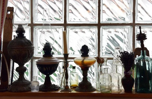 Коллекция старинных масляных ламп перед стеклянной кирпичной стеной — стоковое фото
