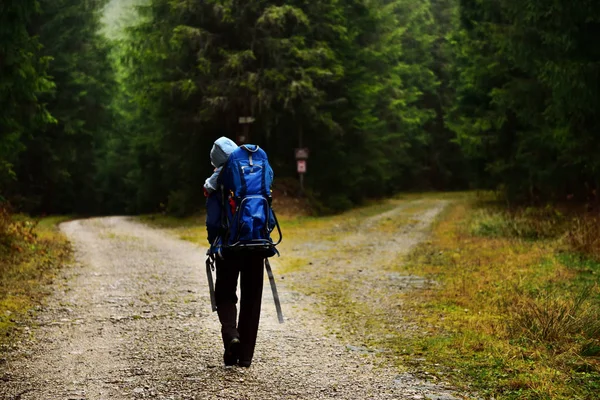 Jovem mãe trekking, carregando seu bebê em uma mochila de bebê — Fotografia de Stock