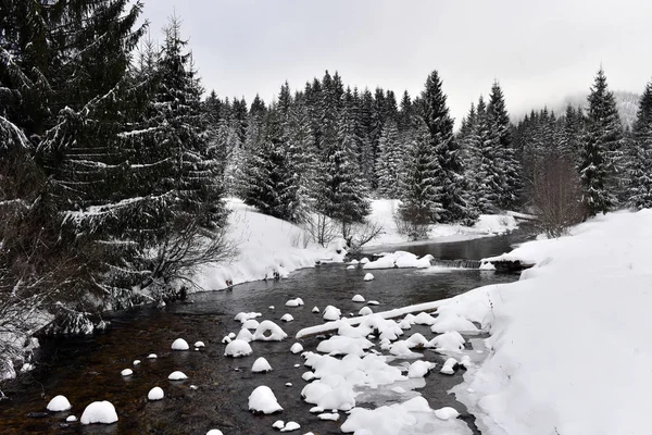 Piccolo fiume ghiacciato con neve fresca sulle rocce — Foto Stock