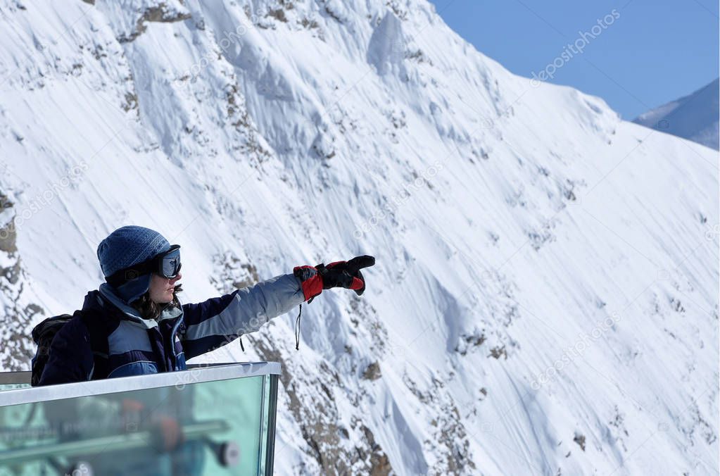 Skier woman in ski clothes and ski googles pointing the directio